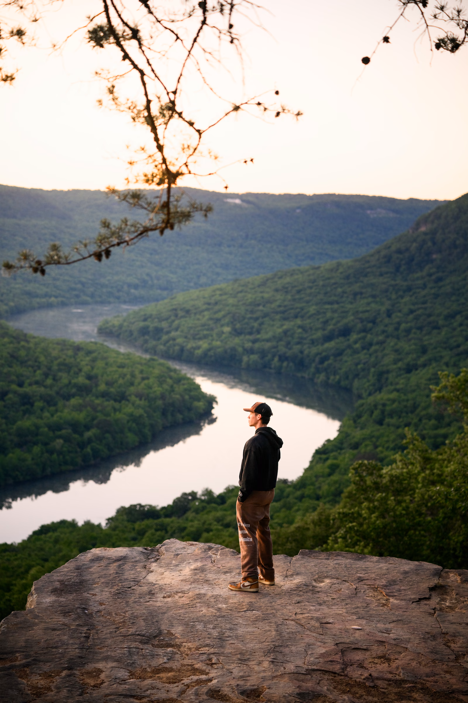 William Lund standing on a rocky overlook above a winding river
