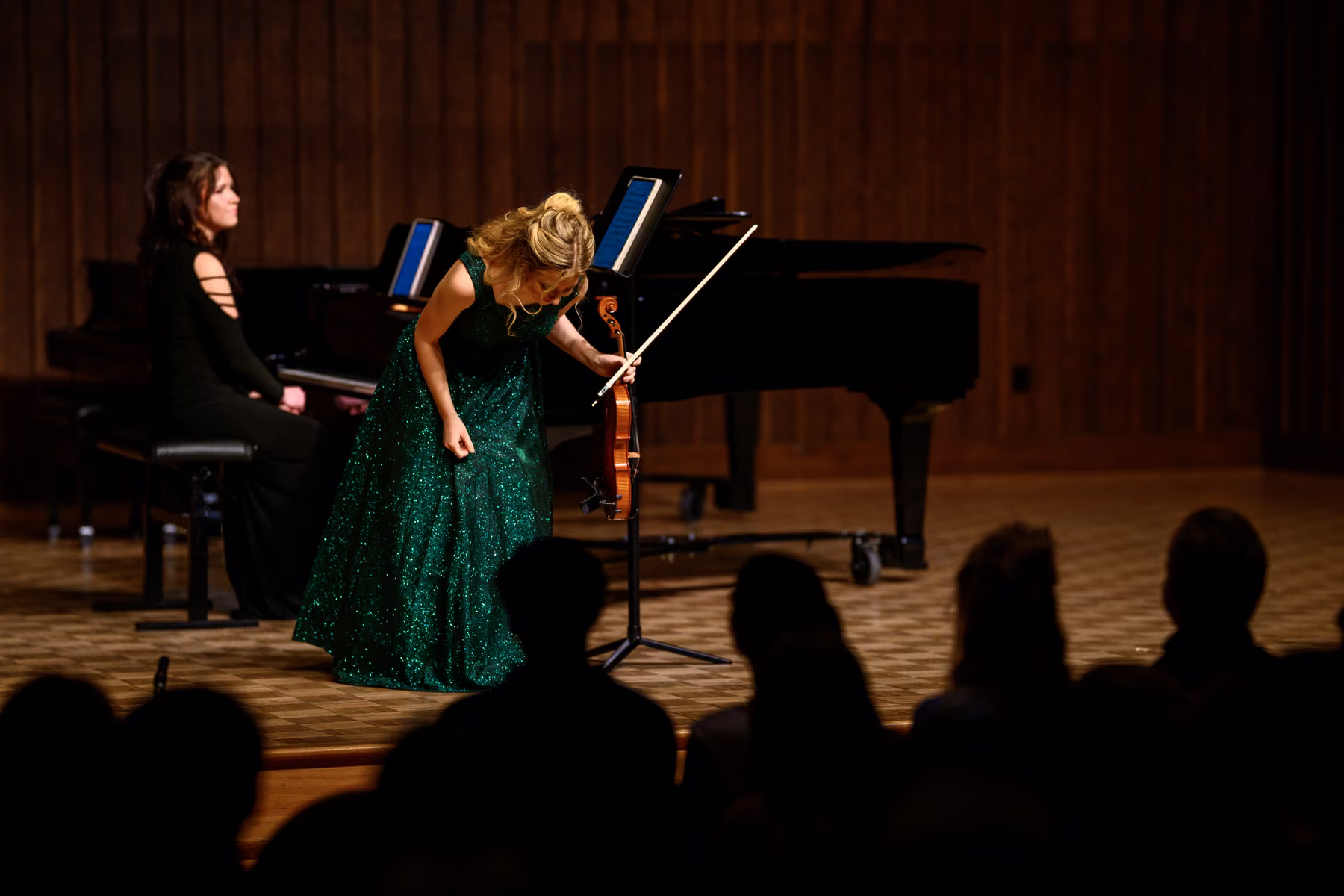 Alyssa bowing to the audience beside the pianist at the end of a piece.
