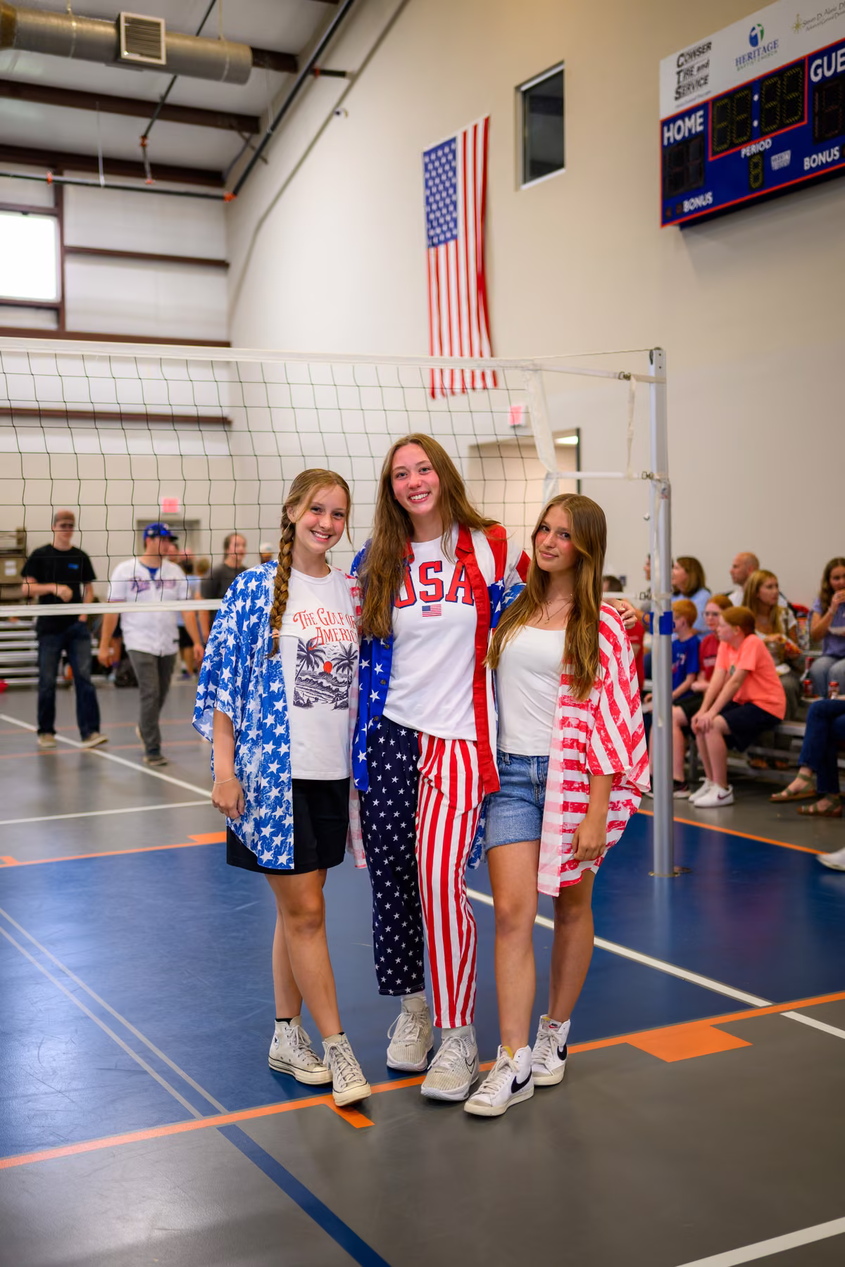 Three guests in red, white, and blue posing beside a volleyball net.