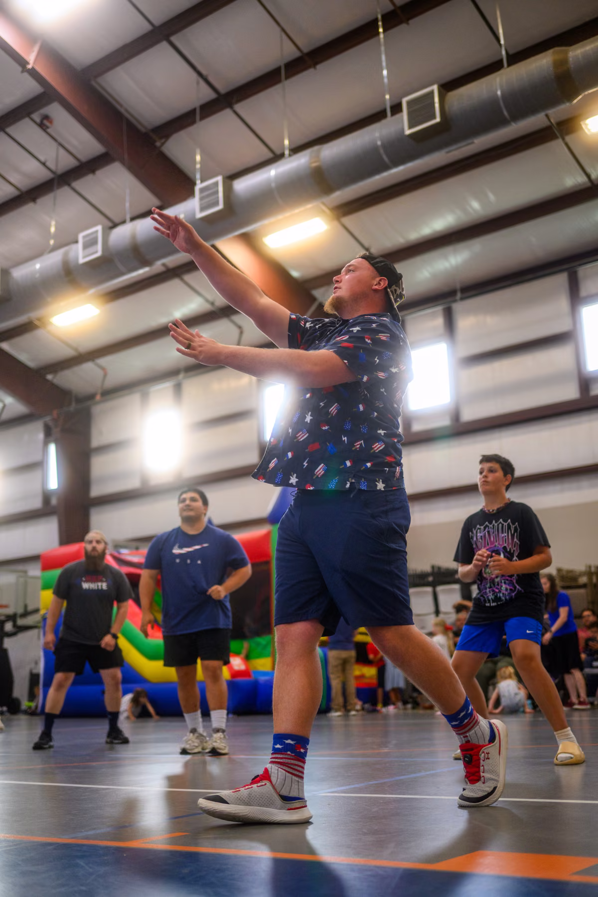 A volleyball player reaching upward during a game in the gym.