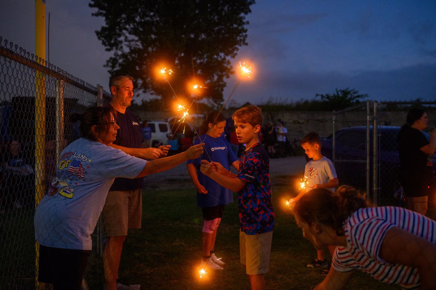 Guests gathering close to light sparklers as evening turns dark.