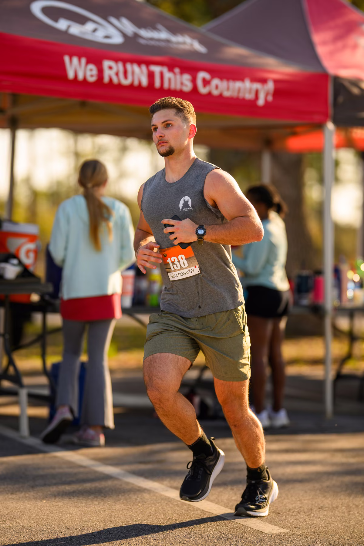 Noah runs past a red event tent wearing race bib 138.
