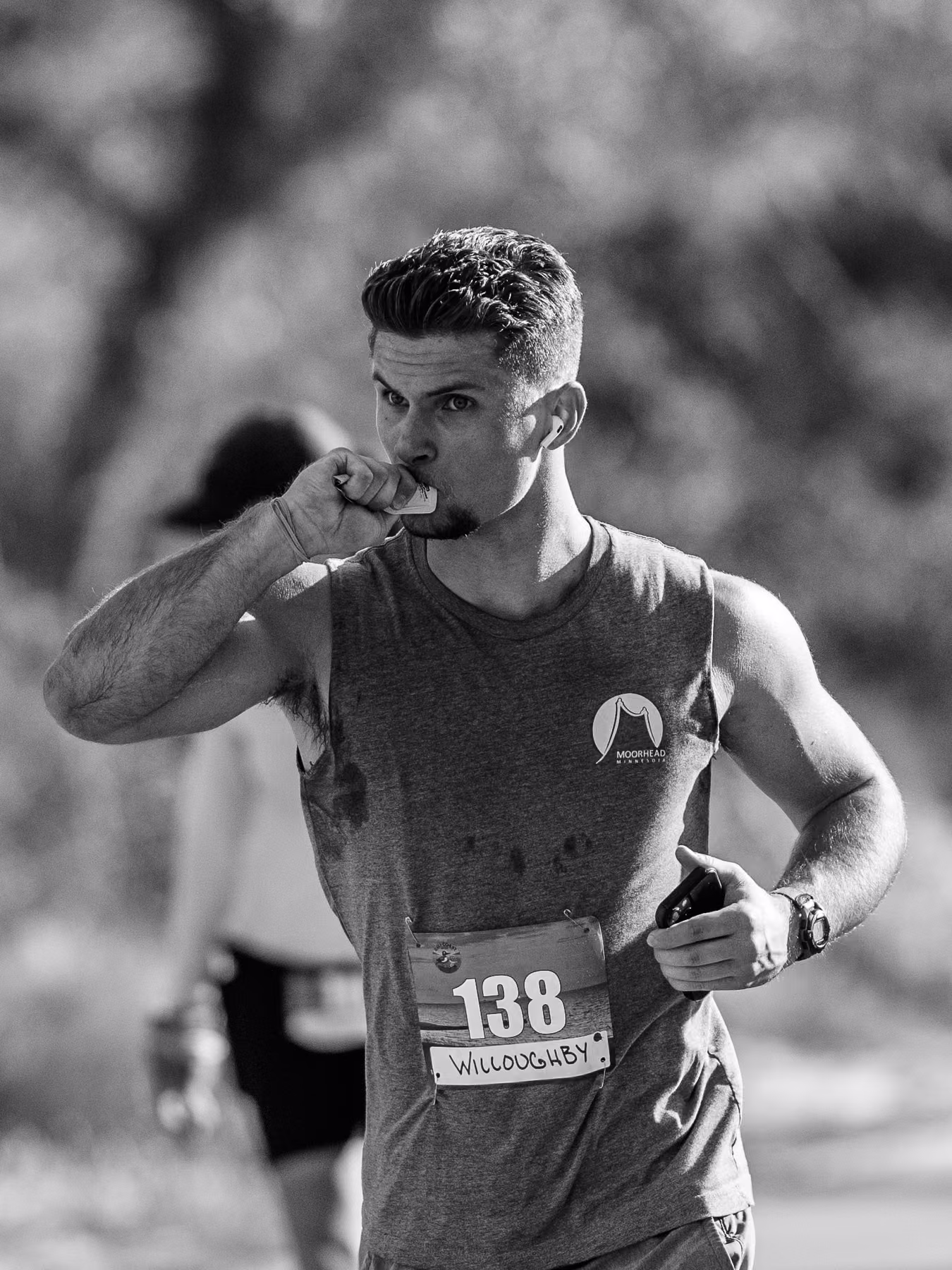 Black-and-white portrait of Noah eating from a small packet while running with race bib 138.