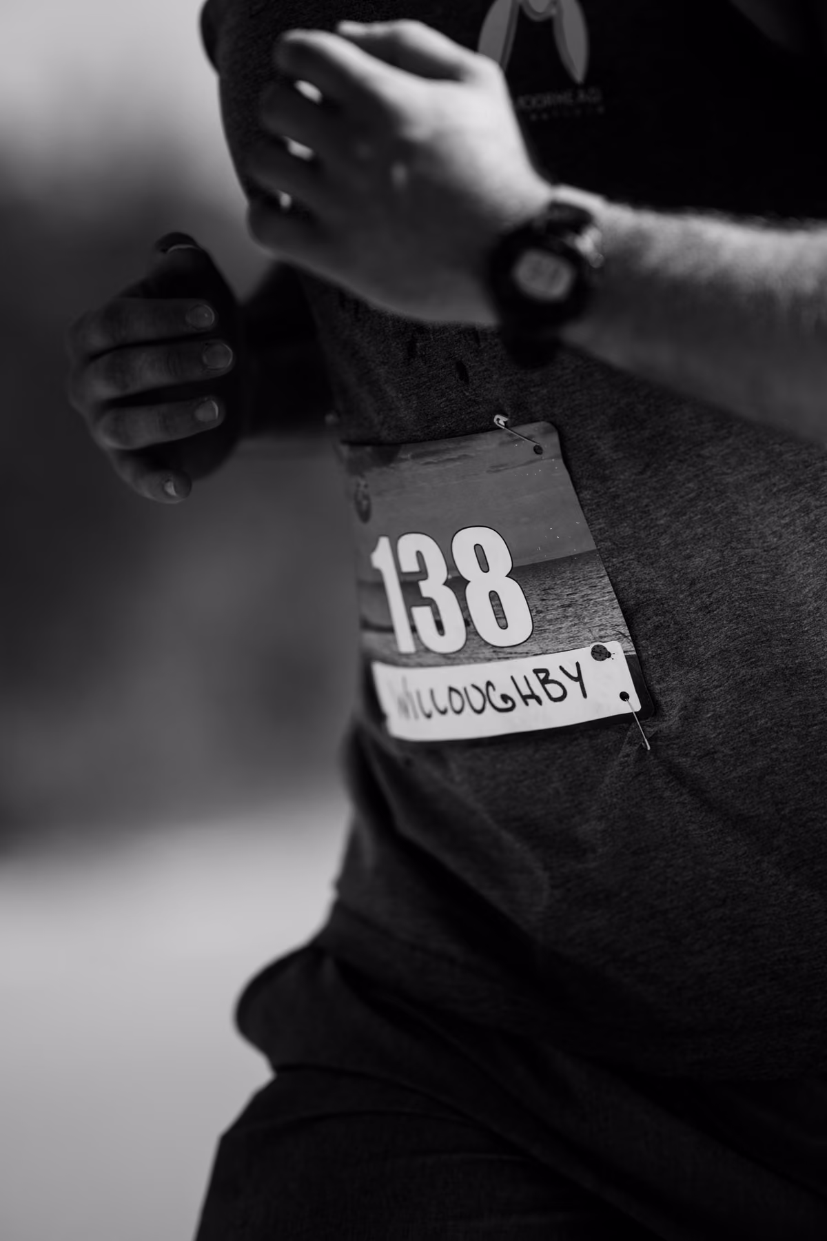 Black-and-white close-up of race bib 138 pinned to Noah’s shirt as he runs.