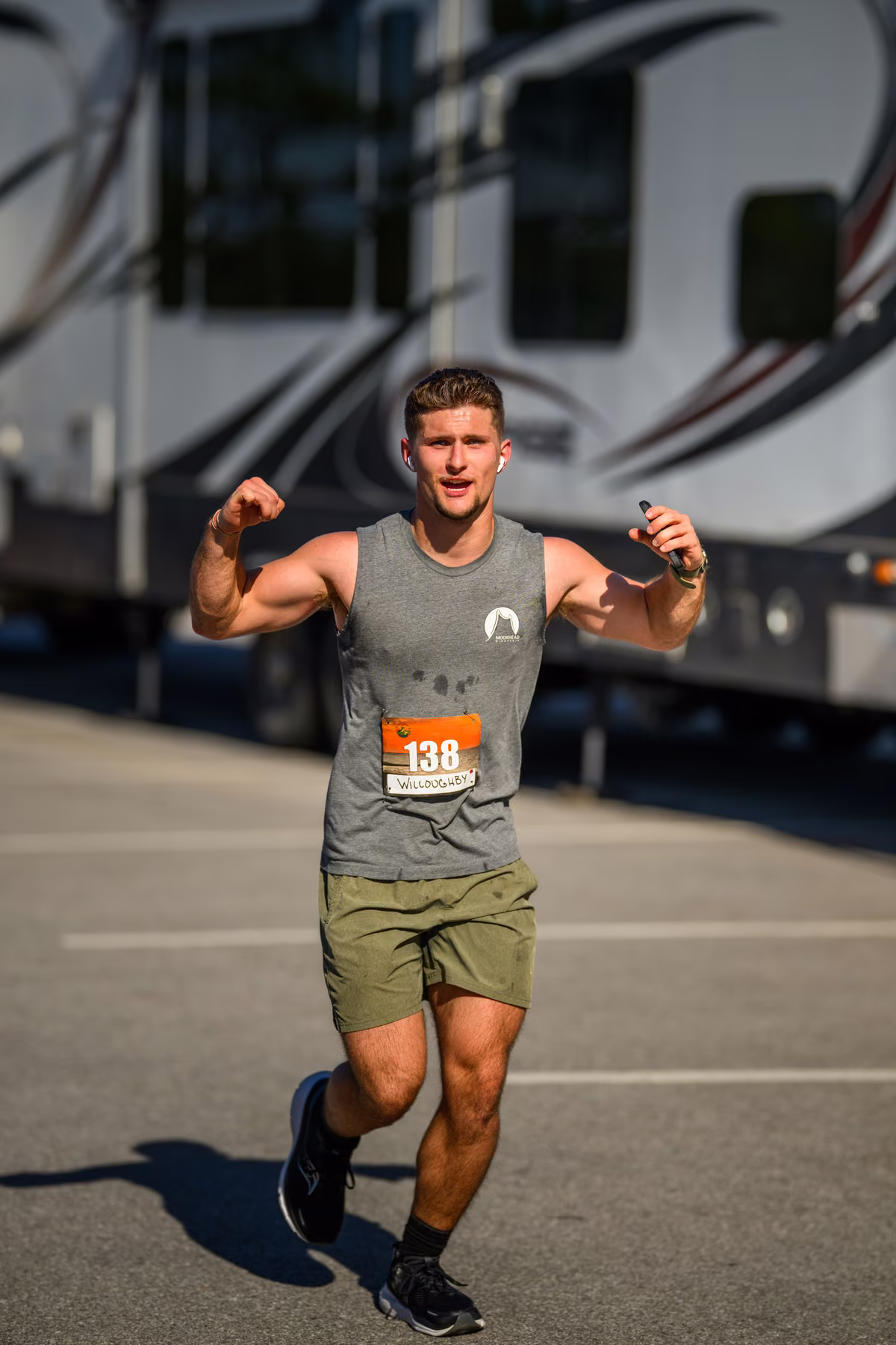 Noah raises his arms toward the camera while running past a parked RV.