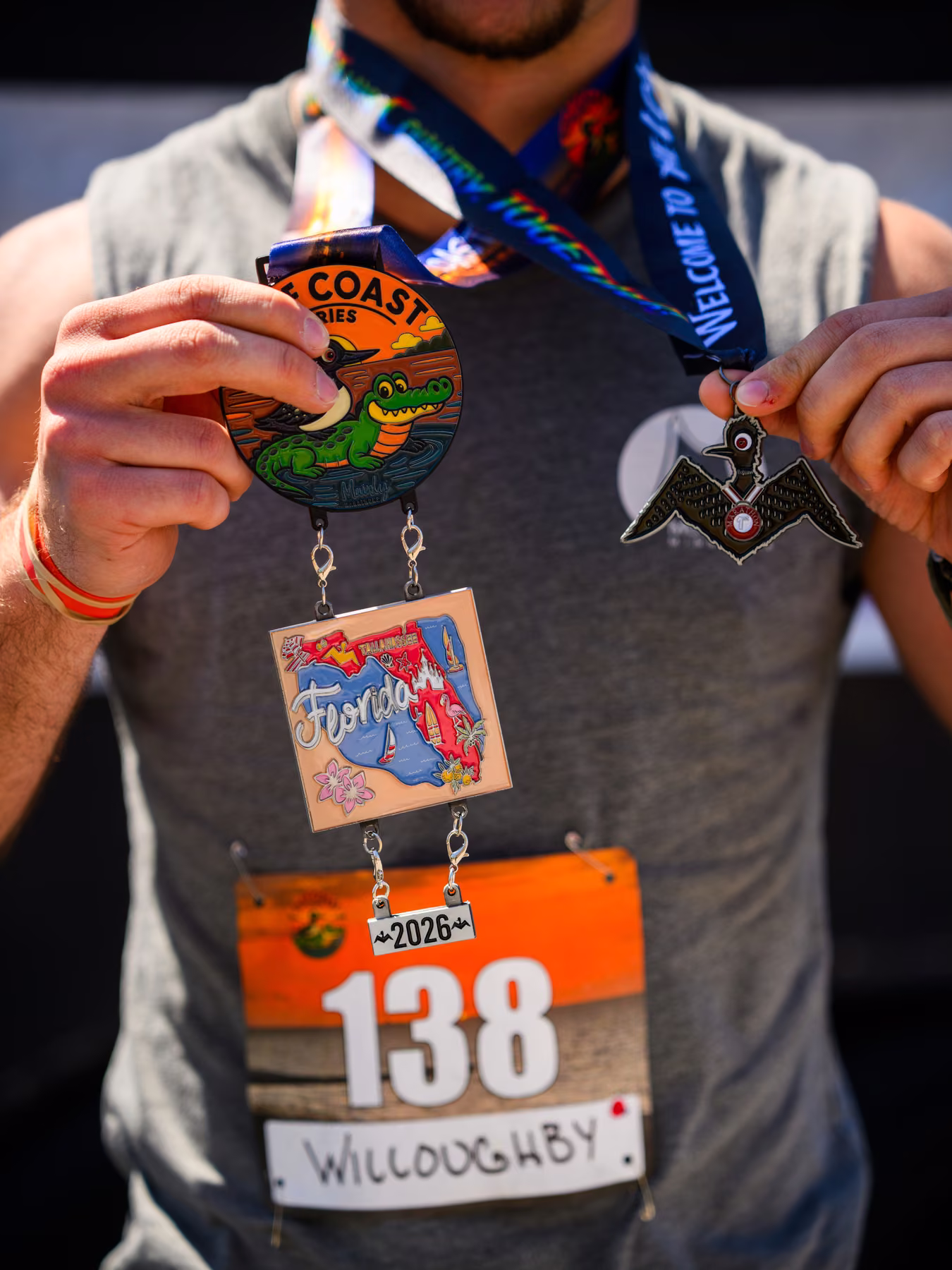 Close-up of Noah holding his colorful race medals above bib 138.