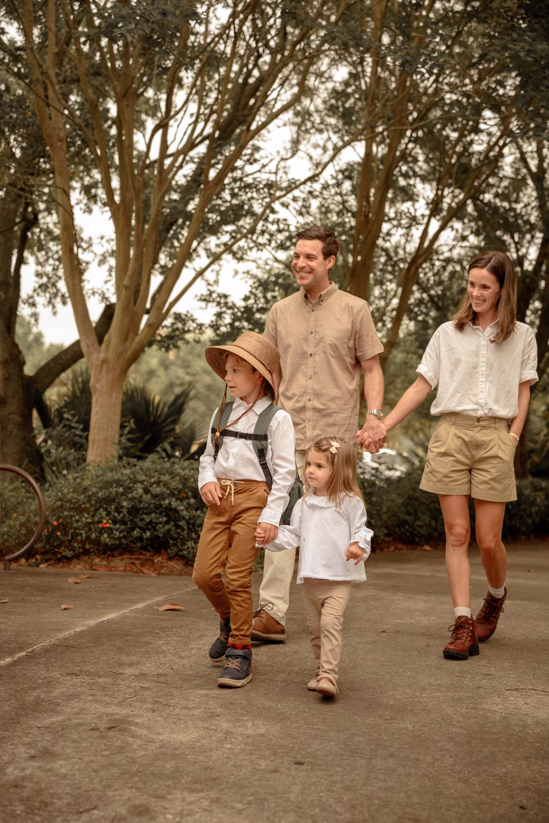 A family of four walking beneath the trees in a warmly edited styled session